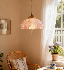 Pink floral lampshade with crystal accents hanging above a rattan chair near a window.