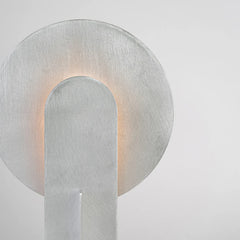 Modern wall sconce with a metallic finish on a light gray background
