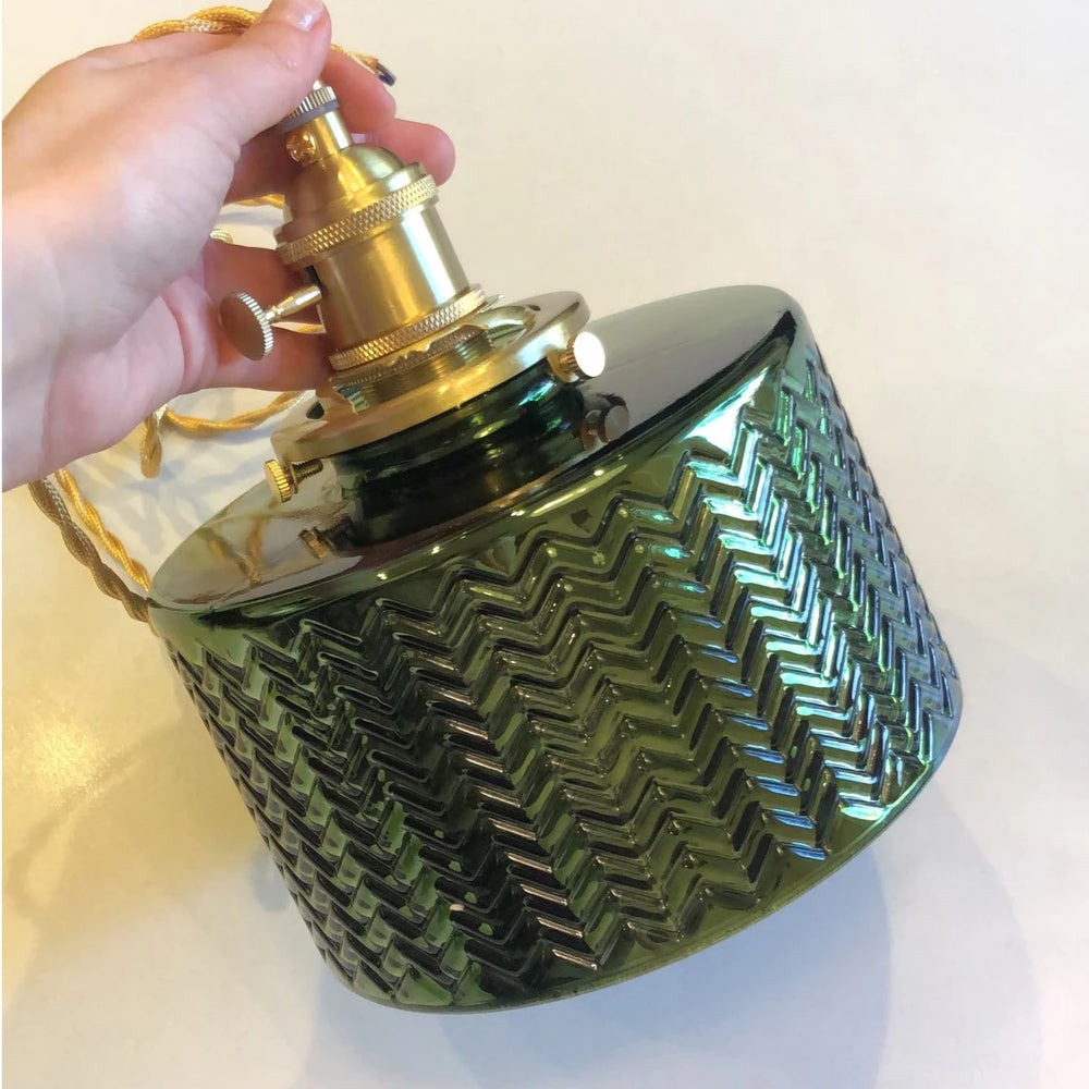 Hand holding a green fluted glass pendant light shade with brass socket