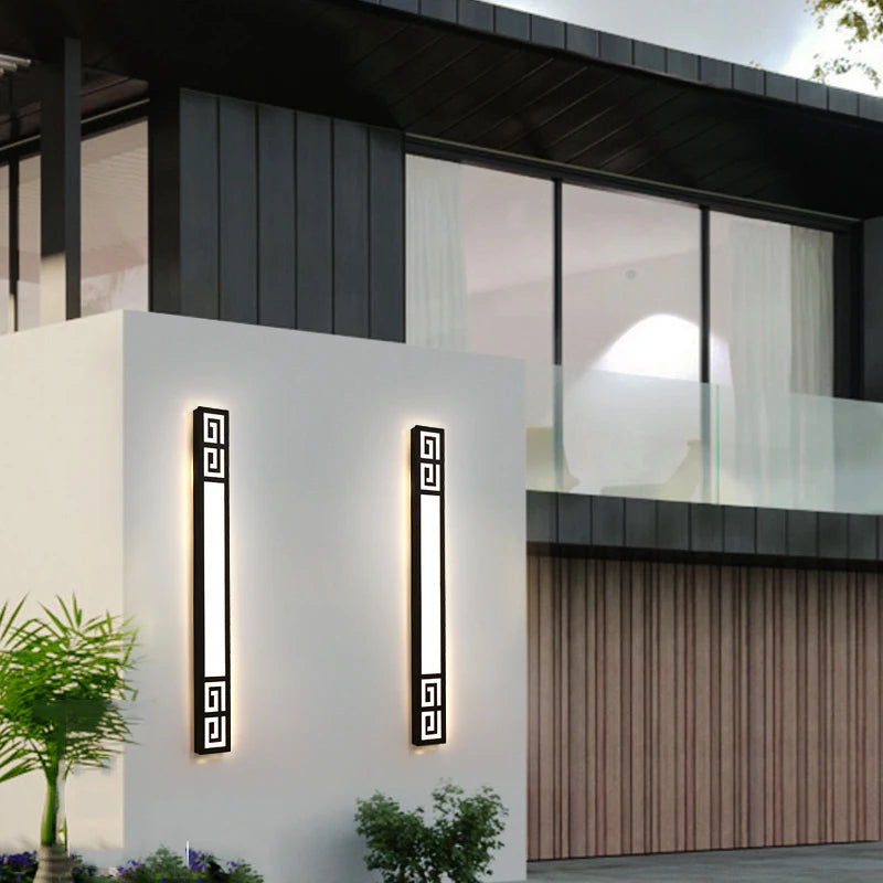 Two black geometric LED wall sconces mounted on a modern building facade, flanking the entrance.
