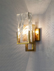 Modern wall sconce with marble-like finish on a textured wall.