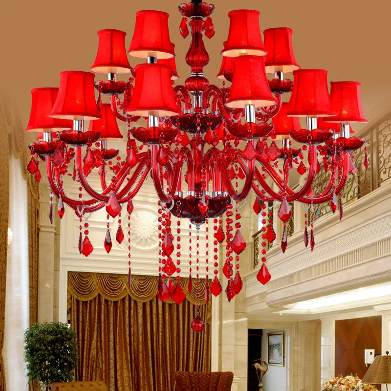 Large red crystal multi-tier chandelier with fabric shades and cascading crystals, in a grand interior setting.