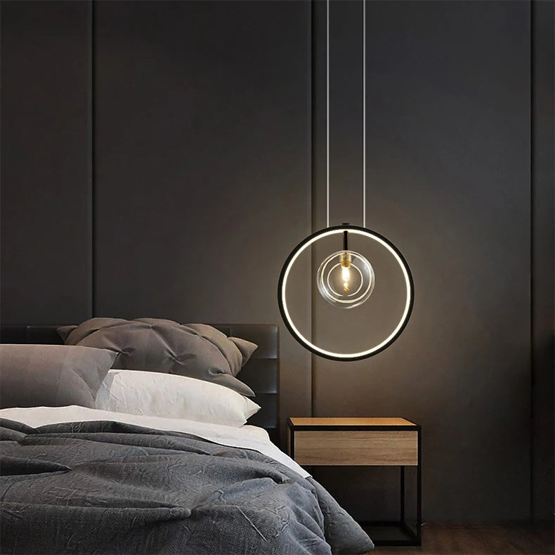 Modern pendant light hanging above a bed in a bedroom setting.