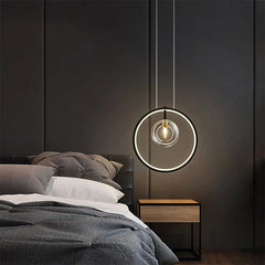 Modern pendant light hanging above a bed in a bedroom setting.