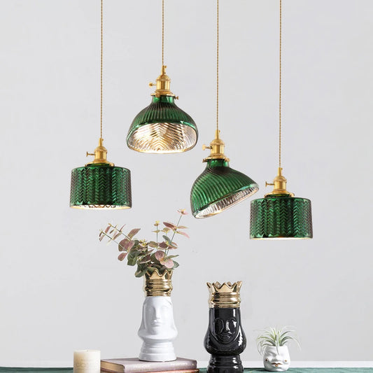 Four green fluted glass pendant lights with brass accents hanging at different heights