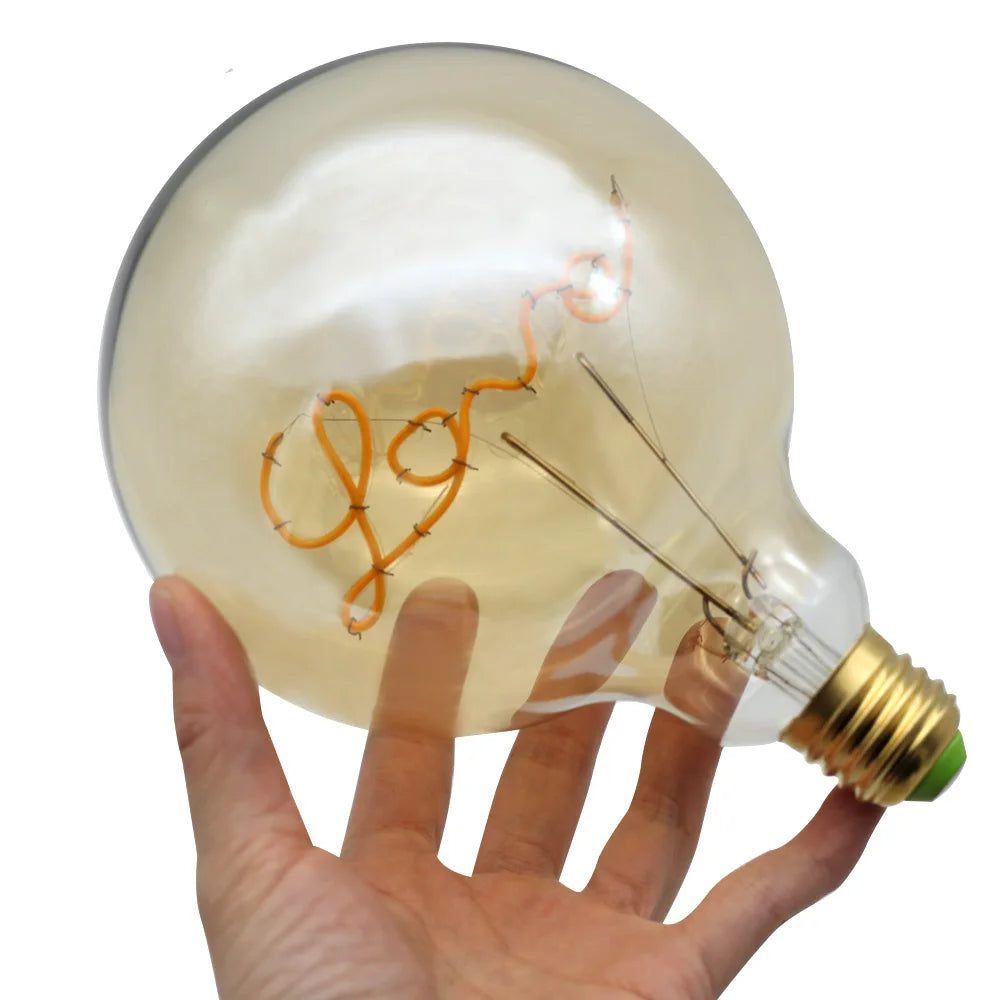 Hand holding a large light bulb with visible filaments on a white background