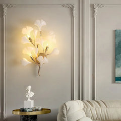 An elegant gold ginkgo leaf wall sconce installed in a room with decorative wall molding.