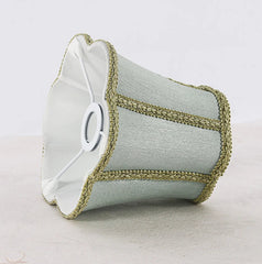 Underside view of a sky blue fabric lampshade showing its white interior and the metal frame for attachment.