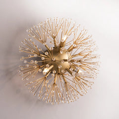 Close-up of a gold sputnik-style wall sconce with radiating arms covered in clear crystals against a white background.