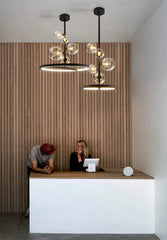 Modern interior with a reception desk and two people, featuring stylish pendant lights.