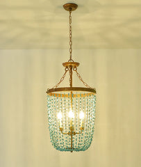 Turquoise stone bead chandelier with a distressed gold frame hanging from a chain against a light-colored ceiling.