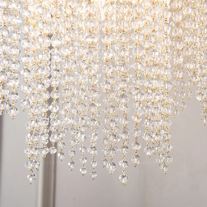 Close-up of a crystal chandelier with clear and gold beads on a neutral background