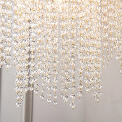 Close-up of a crystal chandelier with clear and gold beads on a neutral background