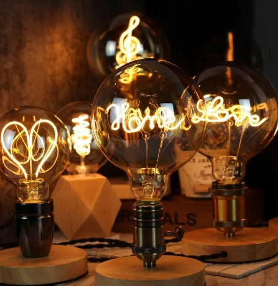 Vintage-style light bulbs with decorative designs on a wooden base.