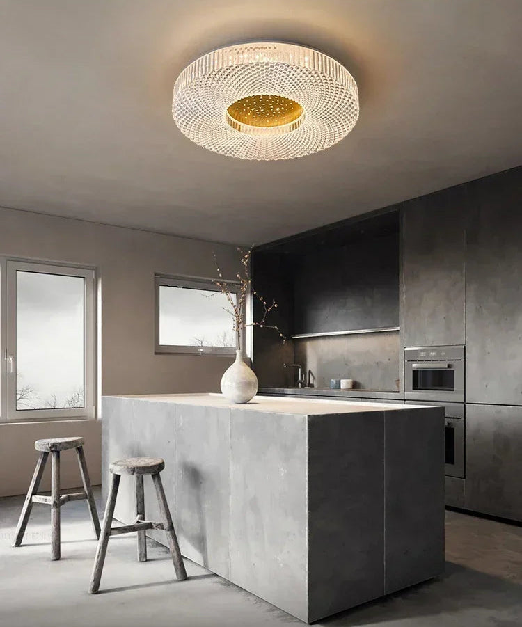 Modern kitchen with a ceiling light fixture, island, and stools.