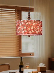 Red floral fabric drum pendant light with wood accents above a dining table