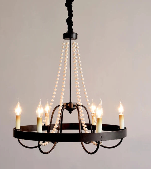 Black chandelier with multiple lit candles against a gray background