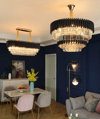 Dining room with two modern chandeliers, a table with flowers, and a sofa.