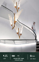 Modern chandelier with leaf-like design hanging over a staircase.