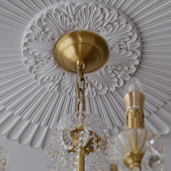 Decorative chandelier with intricate design against a textured ceiling.
