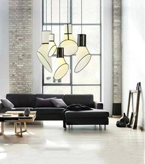 Modern living room with black sectional sofa, glass coffee table, and pendant lights.