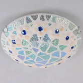 Close-up of a mosaic glass seashell flush mount ceiling light with blue gem accents and iridescent tiles