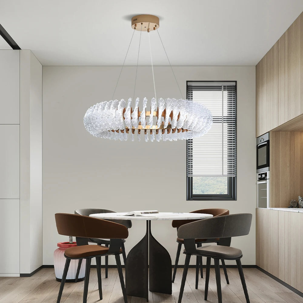 Modern kitchen with a chandelier hanging above a dining table and chairs.