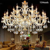 An elegant 12-arm gold crystal candelabra chandelier displayed in a hotel lobby with a grand staircase.