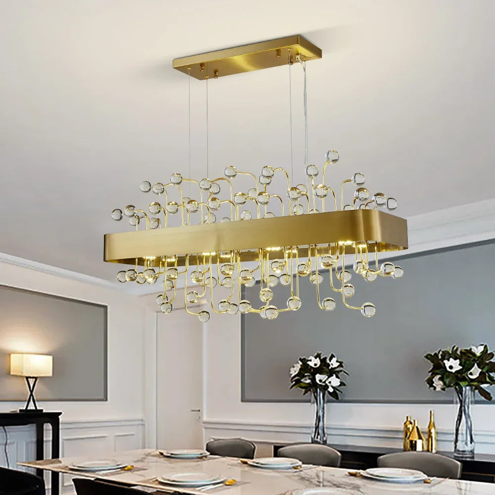 A rectangular gold chandelier with clear crystal accents hanging over a dining table.