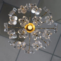Close-up top view of a gold chandelier with multiple clear crystal flower and rectangular accents arranged around a central bulb.
