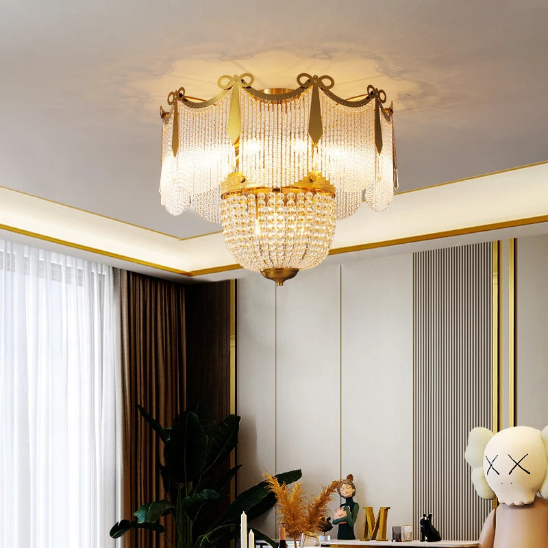 A gold and crystal tiered chandelier in a well-decorated room with white paneling and curtains.