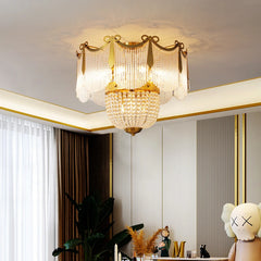 A gold and crystal tiered chandelier in a well-decorated room with white paneling and curtains.