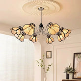 A close-up view of a polished chrome chandelier with light beige, petal-shaped shades accented with black trim.