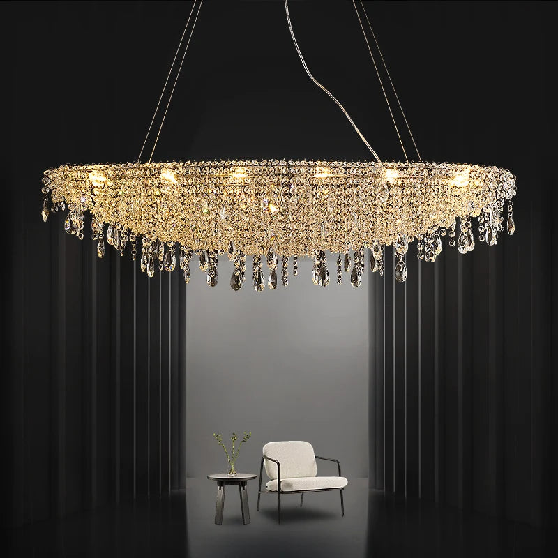 Luxurious crystal chandelier hanging above a modern chair and table in a dimly lit room.
