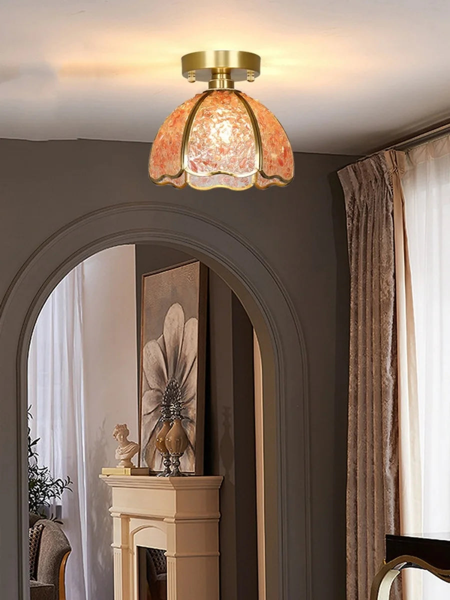 Ceiling light fixture with decorative glass shade in a room with a fireplace and artwork.