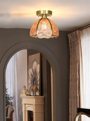 Ceiling light fixture with decorative glass shade in a room with a fireplace and artwork.