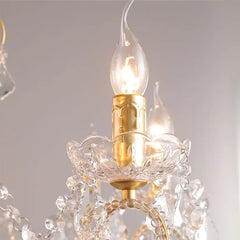 Close-up of a chandelier with crystal details and a lit bulb against a neutral background