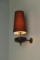 Dark red conical fabric shade wall sconce with a dark wood base mounted on a light wall.