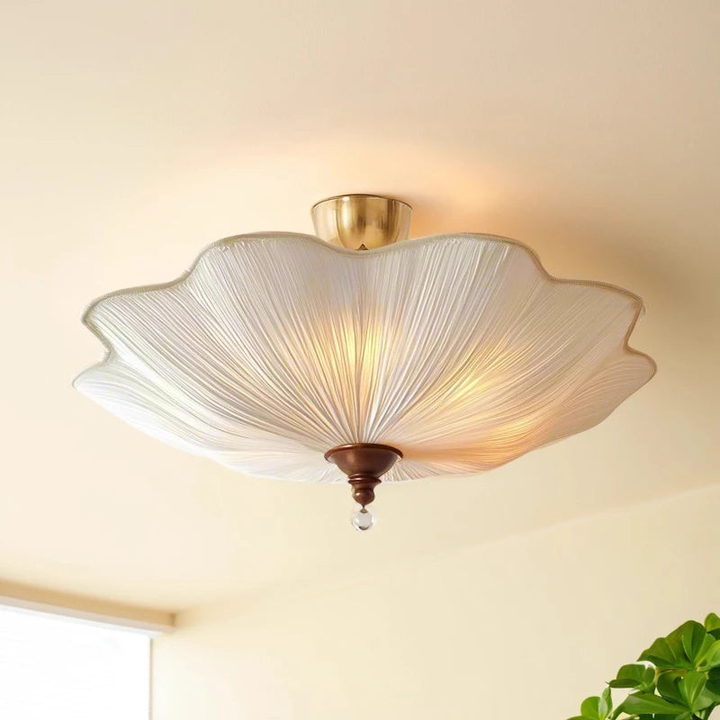 Close-up of the white fabric lotus-leaf shade of a semi-flush ceiling light, showing the textured pleats and gold trim.