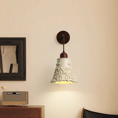 Decorative wall lamp on a beige wall with a framed picture and radio in the background.