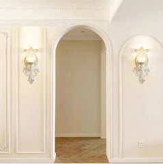 Decorative wall sconces on a white wall with an archway in the background.