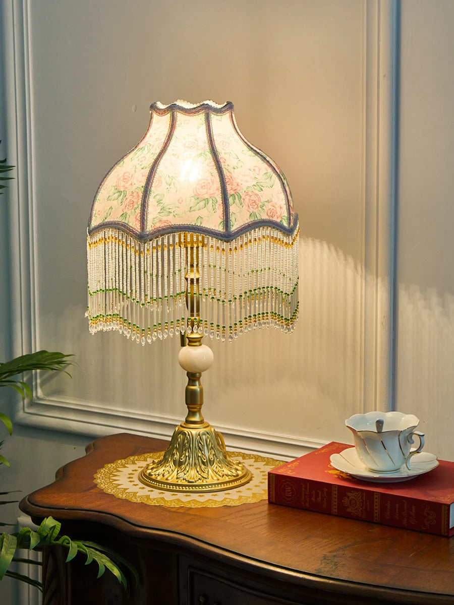 Decorative table lamp with floral lampshade on a wooden surface.