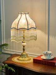 Decorative table lamp with floral lampshade on a wooden surface.