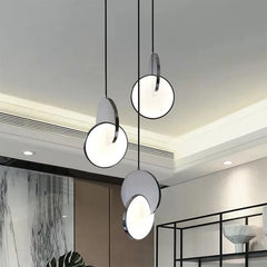 Three polished steel geometric pendant lights hanging from a ceiling.