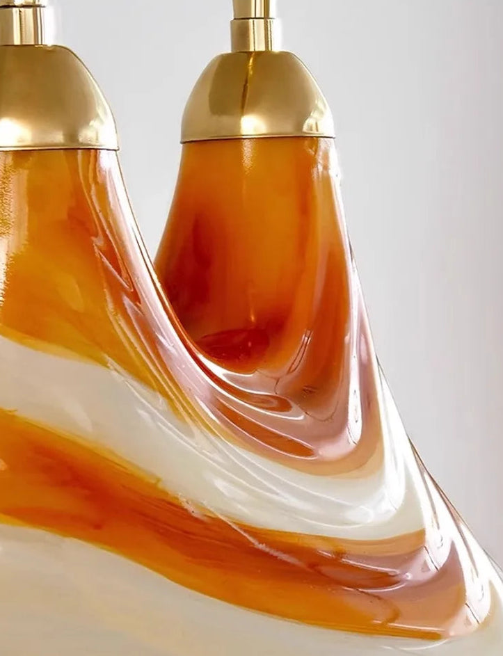 Decorative lamp with gold top and wavy orange and white design on a light gray background