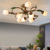 A gold multi-arm ceiling light with white tulip-shaped glass shades and green leaf accents, installed on a ceiling above a grey sofa.