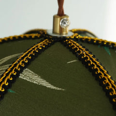Close-up of a green fabric item with gold and black embroidery