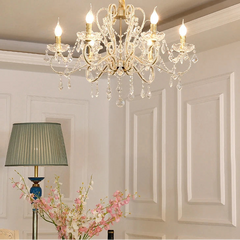 Crystal chandelier in a room with floral arrangement and lamp.