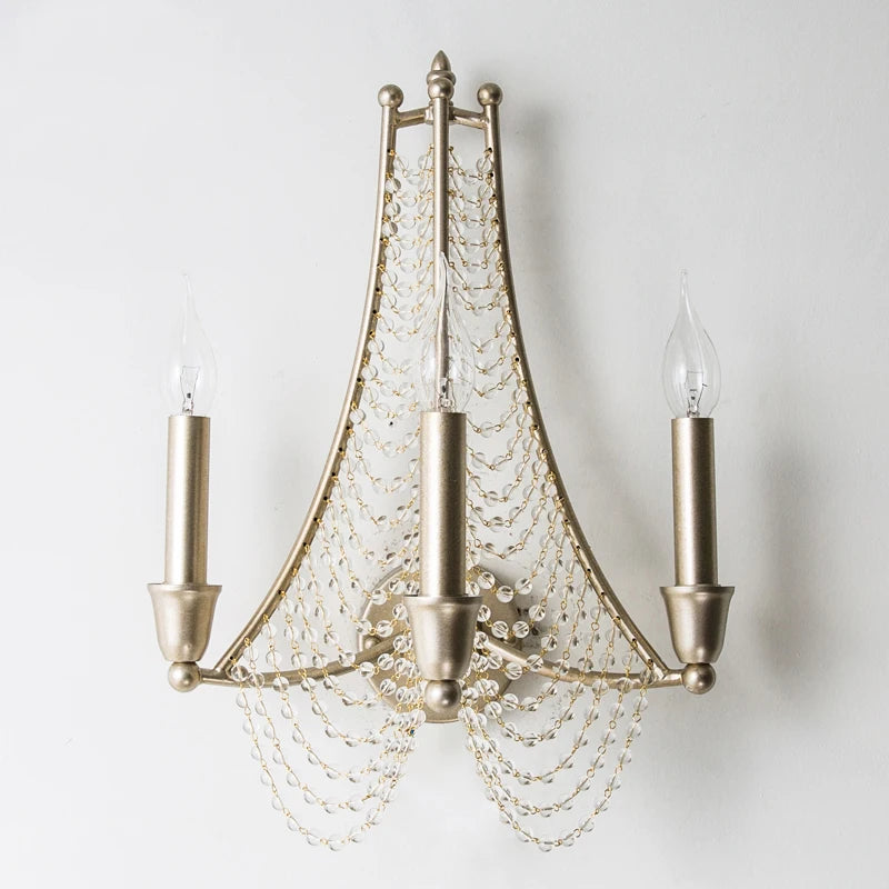 Close-up of the central mounting point of a silver metal wall sconce with crystal bead strands.