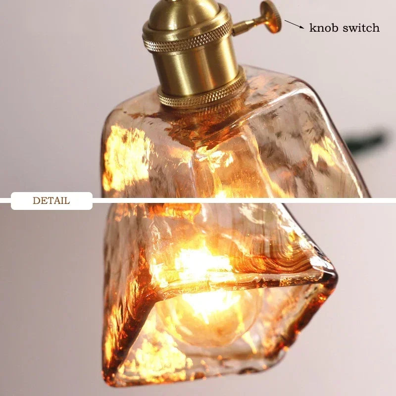 Glass light fixture with a gold knob switch on a gray background